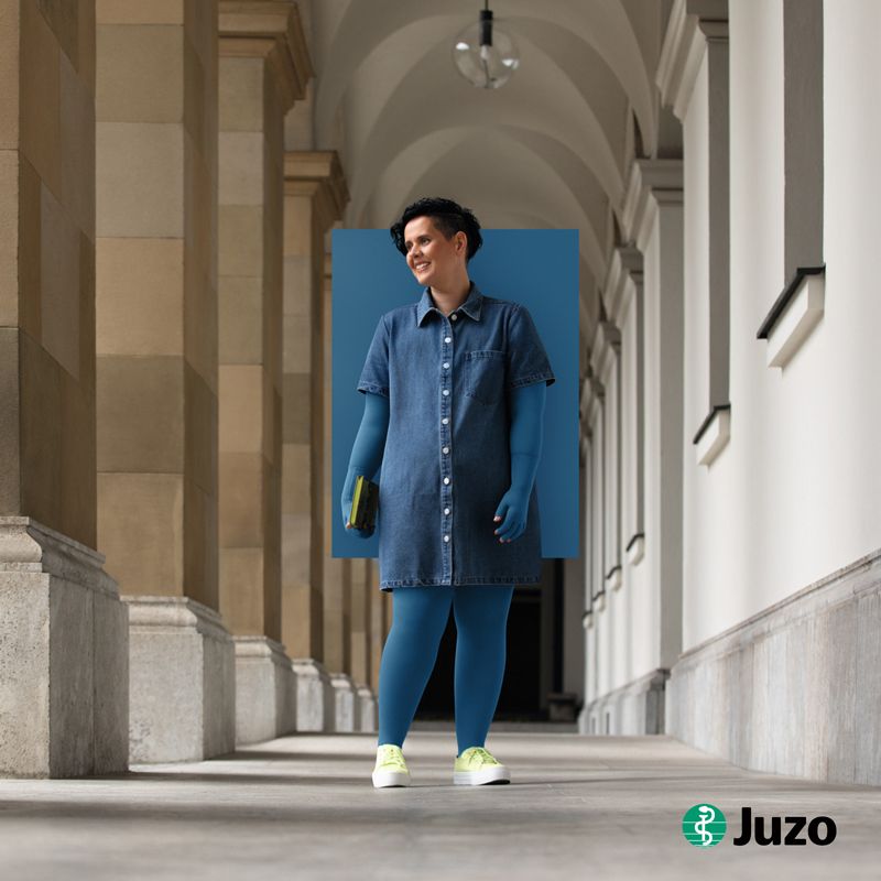 Kompressionsstrümpfe Lipödem und Lymphödem Trendfarben 2026 Sweet Coral Juzo Eine Frau steht vor einem Schloss und trägt Kompressionsstrümpfe in der Farbe Sweet Coral von Juzo zur Kompression bei Lipödem und Lymphödem.