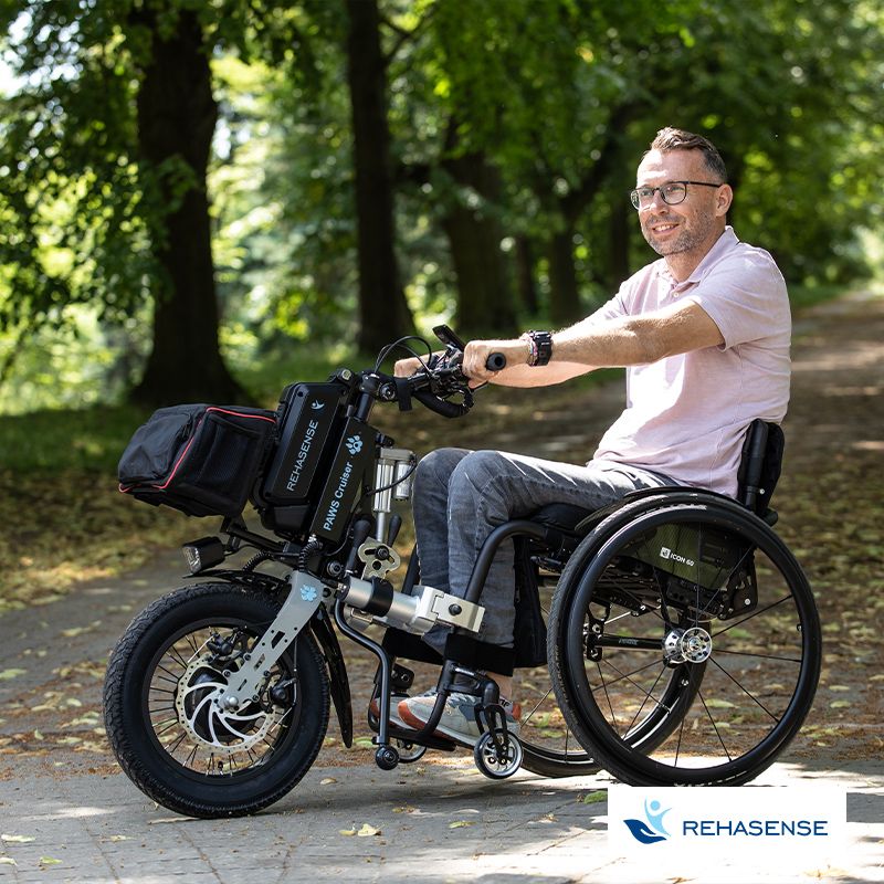 Ein Mann im Rollstuhl benutzt das elektrische Zugsystem und fährt damit im Park.