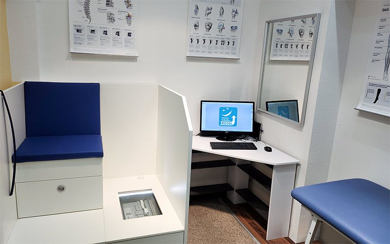 Kabine des Sanitätshauses mit Fußscanner, Liege und PC