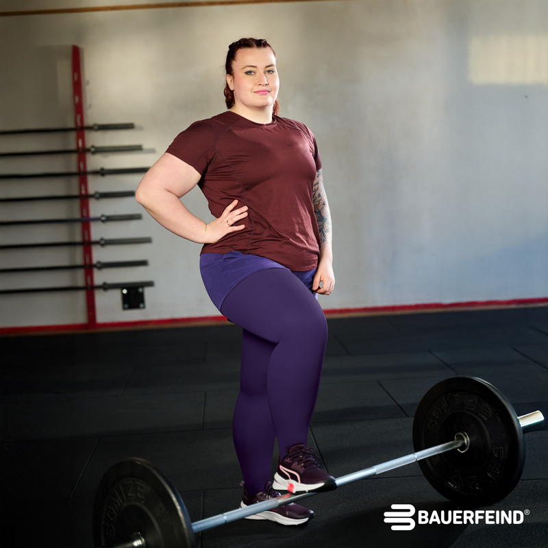 Eine Frau, die im Fitnessstudio trainiert, trägt Kompressionstrümpfe von Bauerfeind