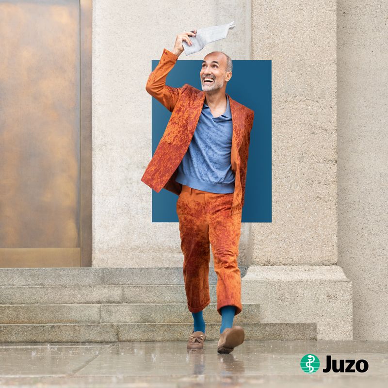 Ein Mann läuft und lacht und trägt dabei Kompressionsstrümpfe von Juzo, die bei Venenleiden helfen.