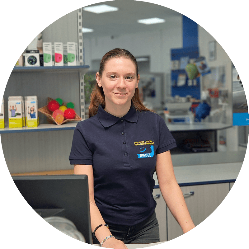 Die Mitarbeiterin steht im Sanitätshaus hinter der Theke.