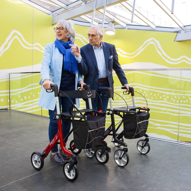 Eine Frau und ein Mann sind mit dem Xeon-Rollator im Einkaufszentrum unterwegs.