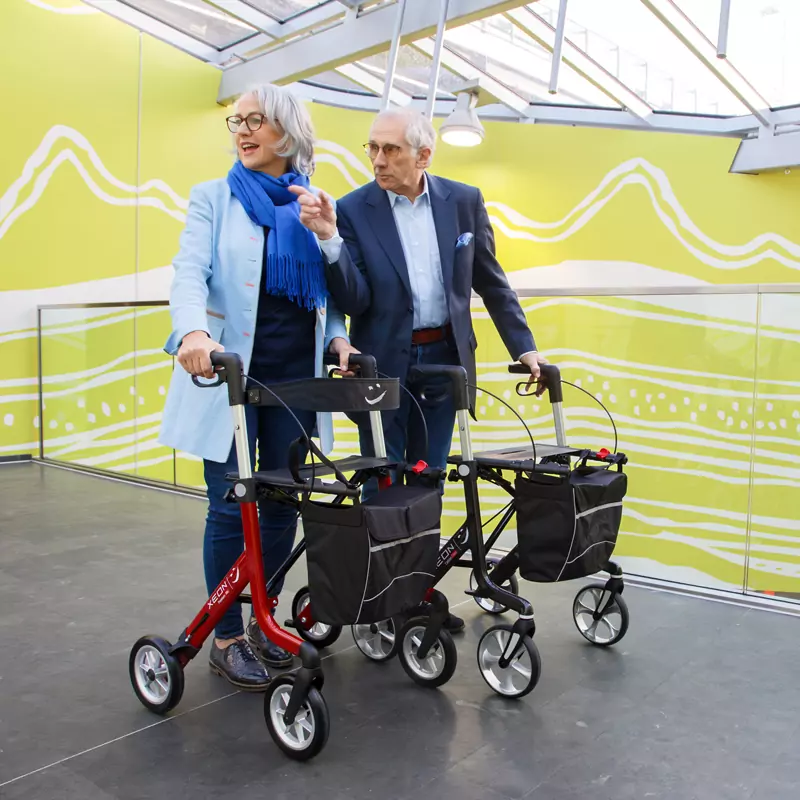 Eine Frau und ein Mann sind mit dem Xeon-Rollator im Einkaufszentrum unterwegs.