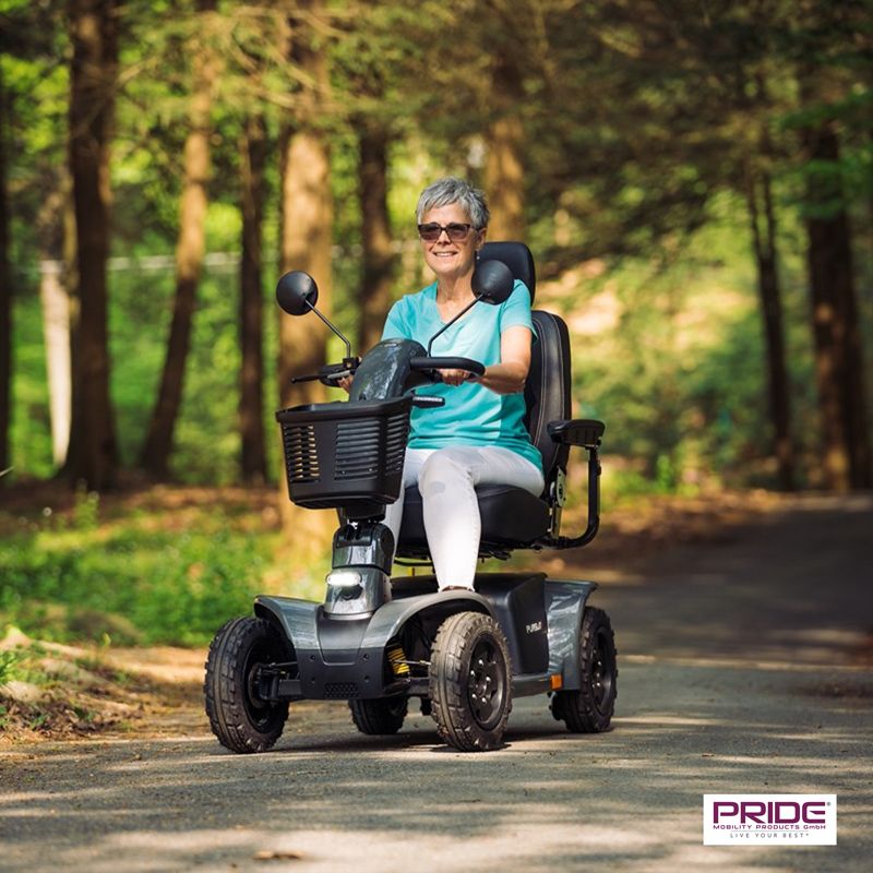 Eine Frau fährt mit dem Pride-Scooter durch den Wald.