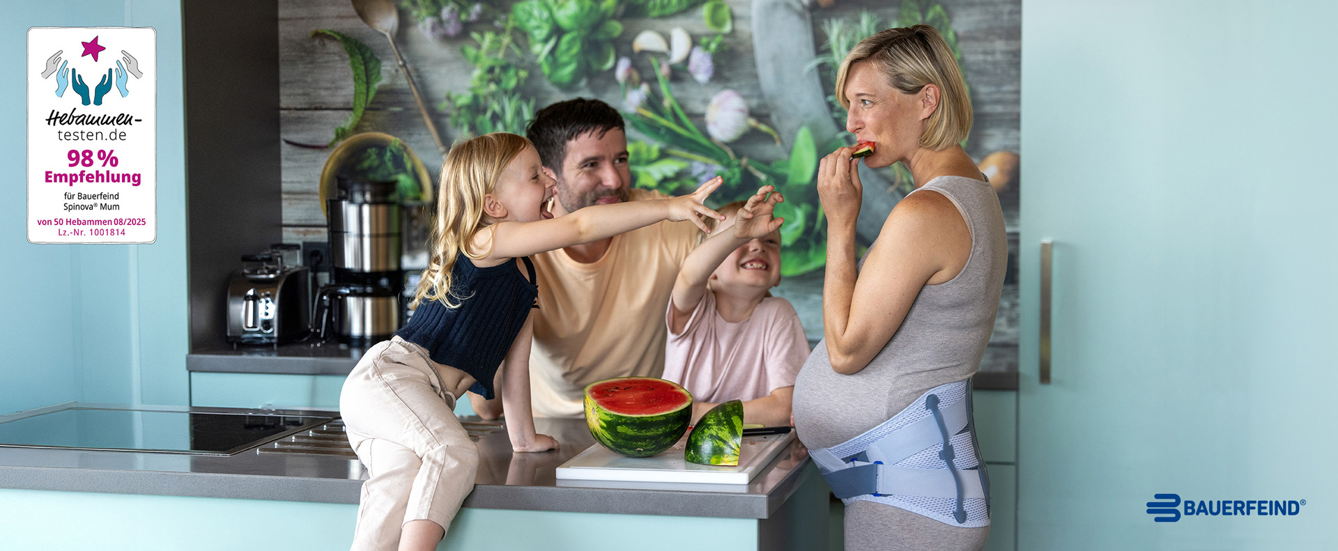 Spinova Mum Schwangerschaftsorthese Hebammen Siegel Bauerfeind Während sie eine Rückenorthese von Bauerfeind trägt, isst eine schwangere Frau mit ihren beiden Kindern und ihrem Mann Wassermelone.