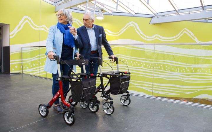 Eine Frau und ein Mann benutzen den Xeon-Rollator im Einkaufszentrum.